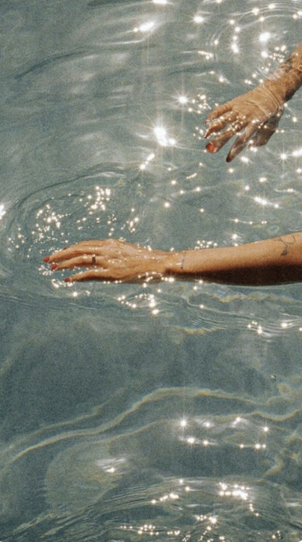 Hands reaching through sparkly water representing quantum entanglement and interconnection